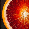 An extreme close-up of a sliced blood orange, showing its deep red and orange marbled pulp.