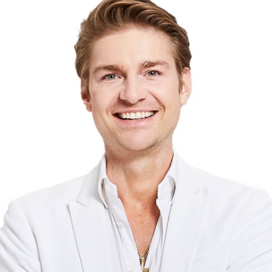 A headshot of a smiling man with blond hair and blue eyes wearing a white shirt and jacket.