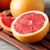 A whole grapefruit and a halved grapefruit with pink flesh, along with several wedges, on a wooden surface.